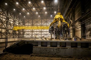 A crane claw grabbing waste at a facility.
